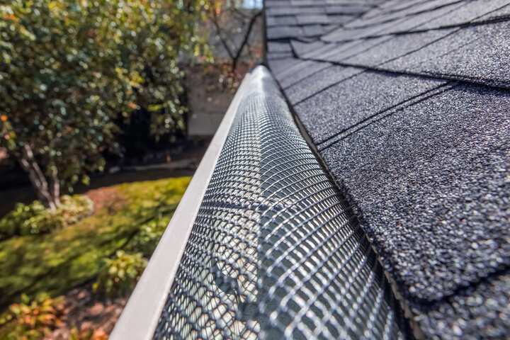 A contractor demonstrating the effectiveness of a gutter guard to a potential client in Tulsa